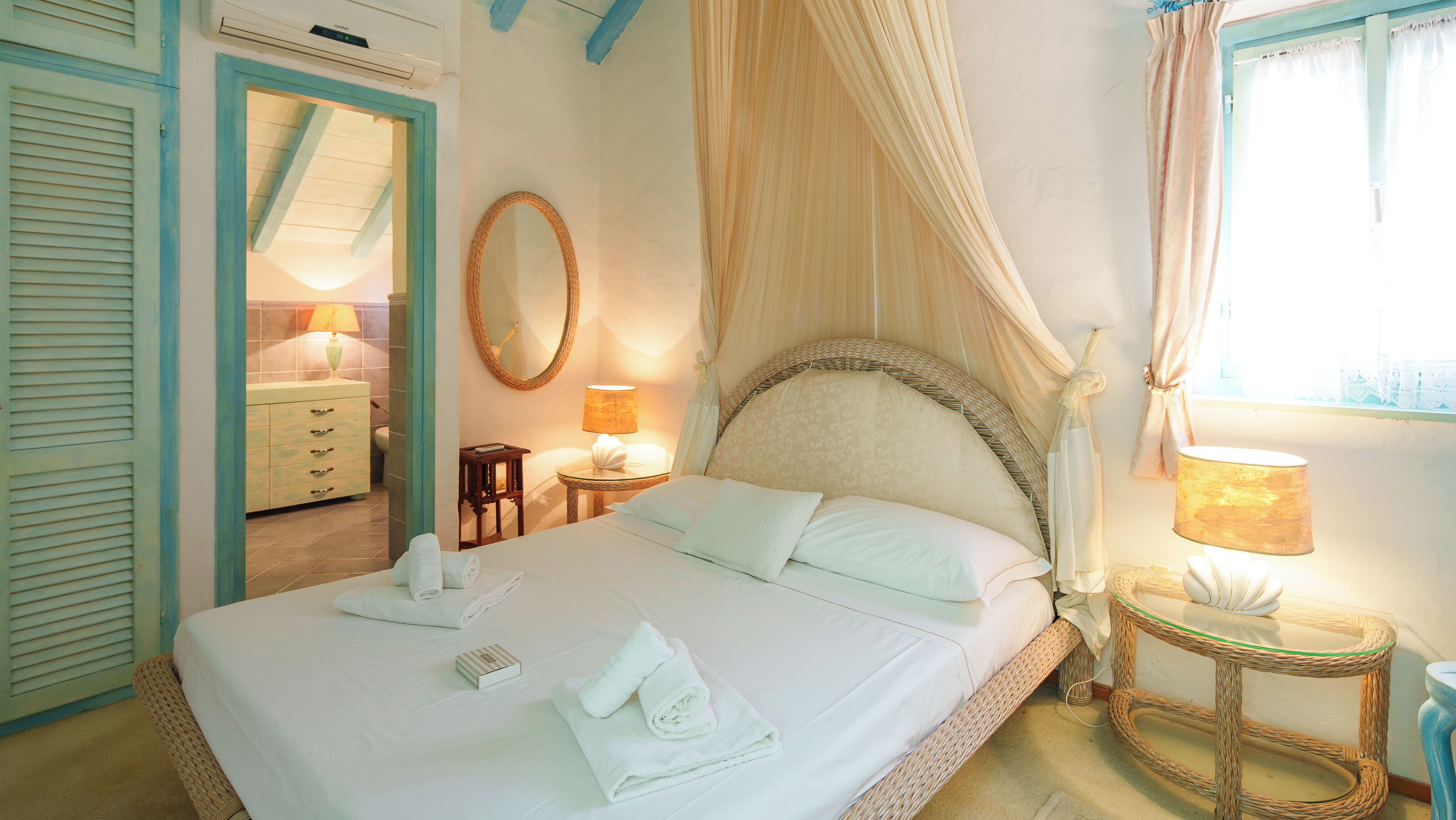 A bedroom with a bed, bedside tables, a mirror, and a window with curtains.