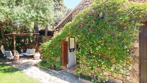 Un edificio in pietra con una pergola in legno e posti a sedere all'aperto.