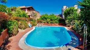 Una piscina circondata dal verde, con un edificio in pietra e un pontile in legno.