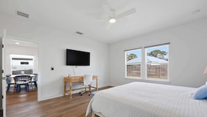 Une chambre à coucher avec un lit, un bureau, une chaise, une télévision et une fenêtre donnant sur un beau paysage.