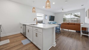 Une cuisine moderne avec des meubles blancs, un îlot central et des luminaires suspendus.