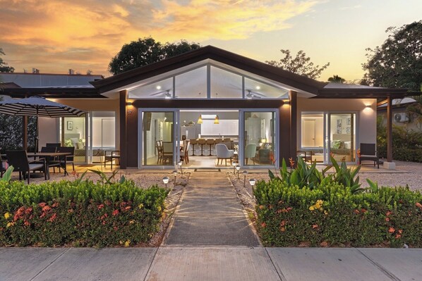 Ein modernes Haus mit Terrasse, Essbereich und Wohnzimmer mit einem großen Glasfenster.