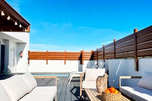 Eine Dachterrasse mit Außenmöbeln, einem Pool und einem Holenzaun.