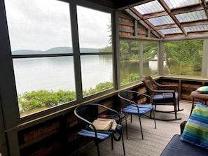 Ein überdachter Außenbereich mit Blick auf einen See und Hügel.