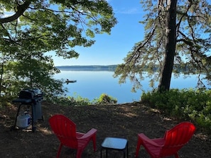 Eine Grillplatz am See mit roten Stühlen.