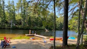 En campingplads ved søen med en anløbsbro, både og en stol.