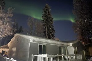 A house with a snow-covered deck and a view of the northern lights. - Aurora Hideaway (Fairbanks)