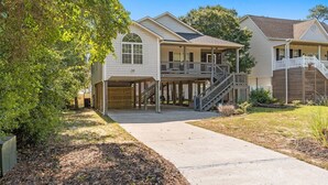 A two-story house with a covered porch, a staircase, and a driveway. - Experience Oak Island at Stitch by the Sea, a cozy 3-bedroom retreat for 10. (Oak Island)