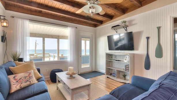 Een woonkamer met een bank, een salontafel, een televisie en uitzicht op het strand.