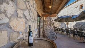 A stone wall, a wooden barrel, a bottle of wine, and a hanging chair.