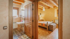 A bedroom with a wooden ceiling, a bed with a headboard, a bedside table, and a window.