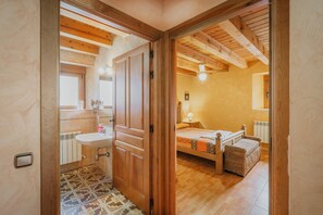 A bedroom with a wooden ceiling, a bed with a headboard, a bedside table, and a window.