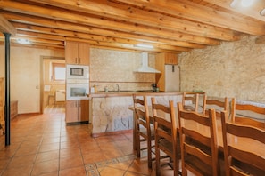 Une cuisine avec des meubles en bois, un mur en pierre et un sol carrelé.