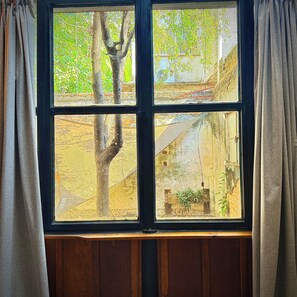A window with a view of a tree and a building. - Basilio Studio (Puerto Vallarta)