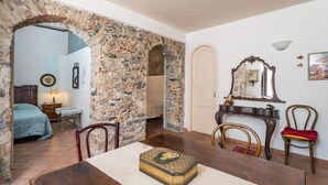 A room with a stone archway, a bed, a table with a box, and a mirror on the wall.