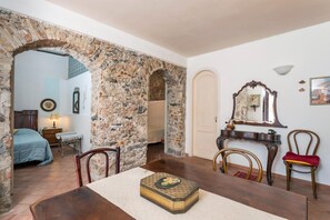 A room with a stone archway, a bed, a table with a box, and a mirror on the wall.