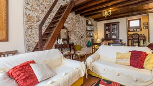 A cozy room with two beds, a stone wall, a wooden staircase, and a dining area.