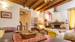 A cozy living room with a wooden ceiling, a fireplace, a dining table, and a sofa.