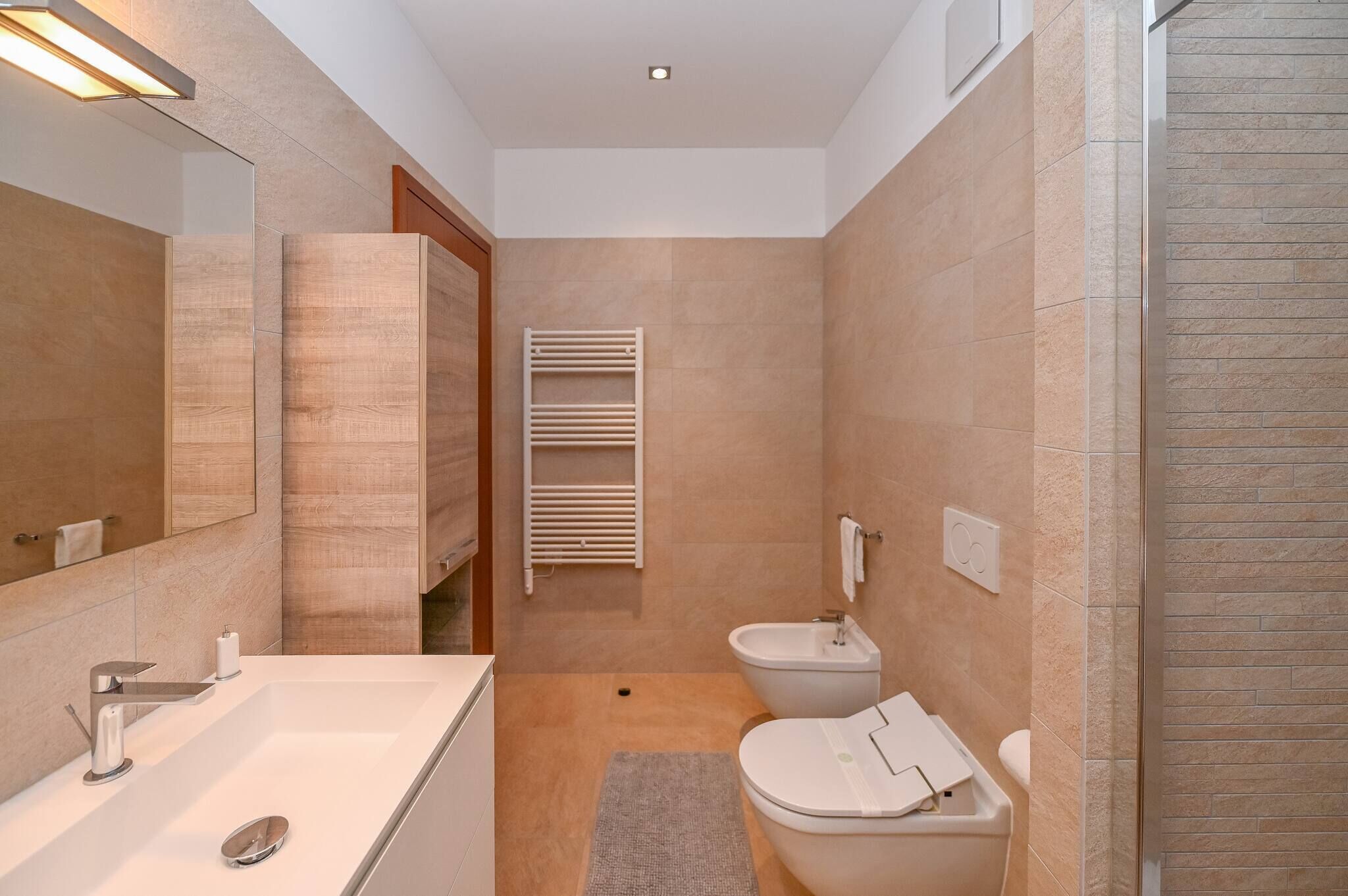 A modern bathroom with a bathtub, toilet, bidet, and a towel rack.