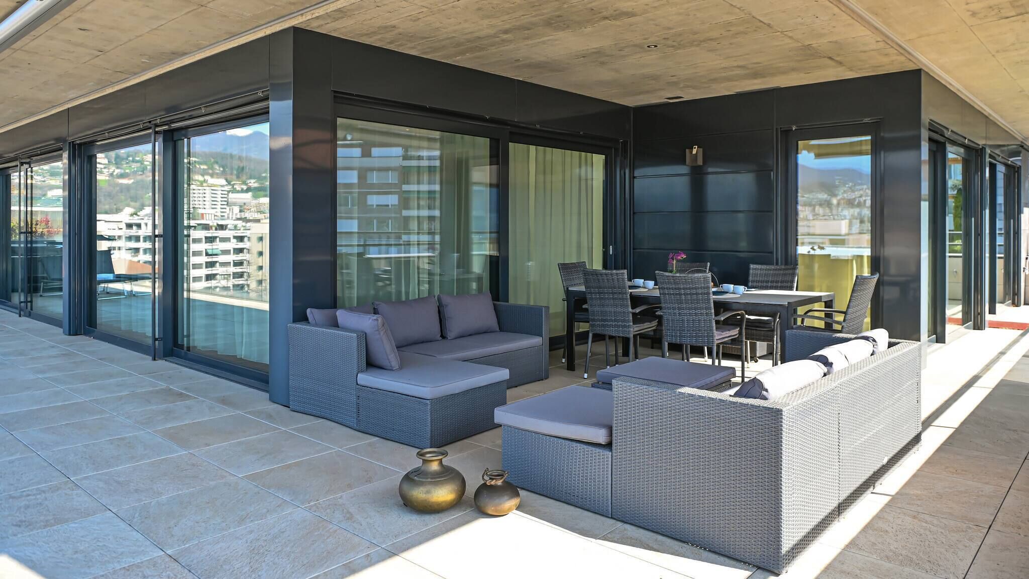 Un espace de détente extérieur moderne, comprenant un canapé, des fauteuils et une table à manger.