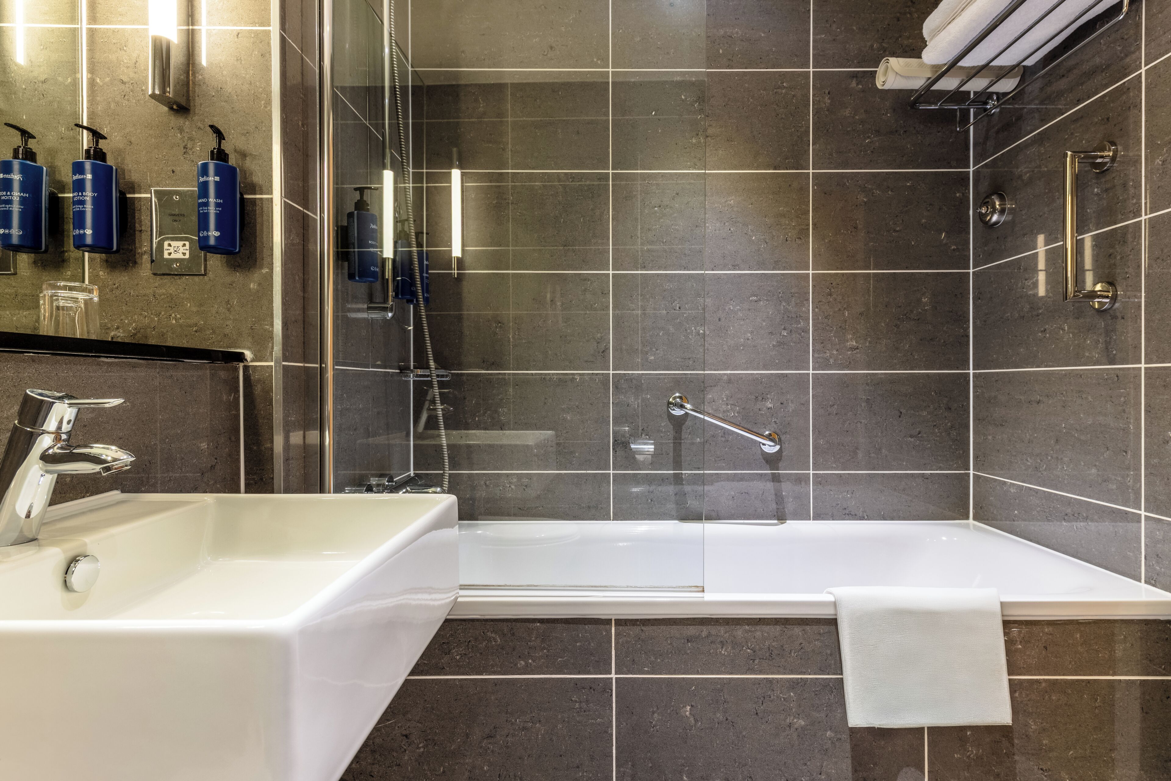A modern bathroom with a bathtub, a sink, and a glass shower enclosure.