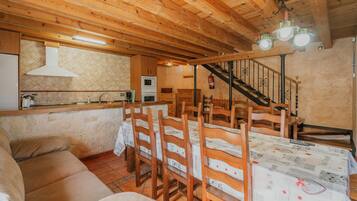 Un interior de madera con una mesa de comedor, sillas, un sofá, una zona de cocina y una escalera.
