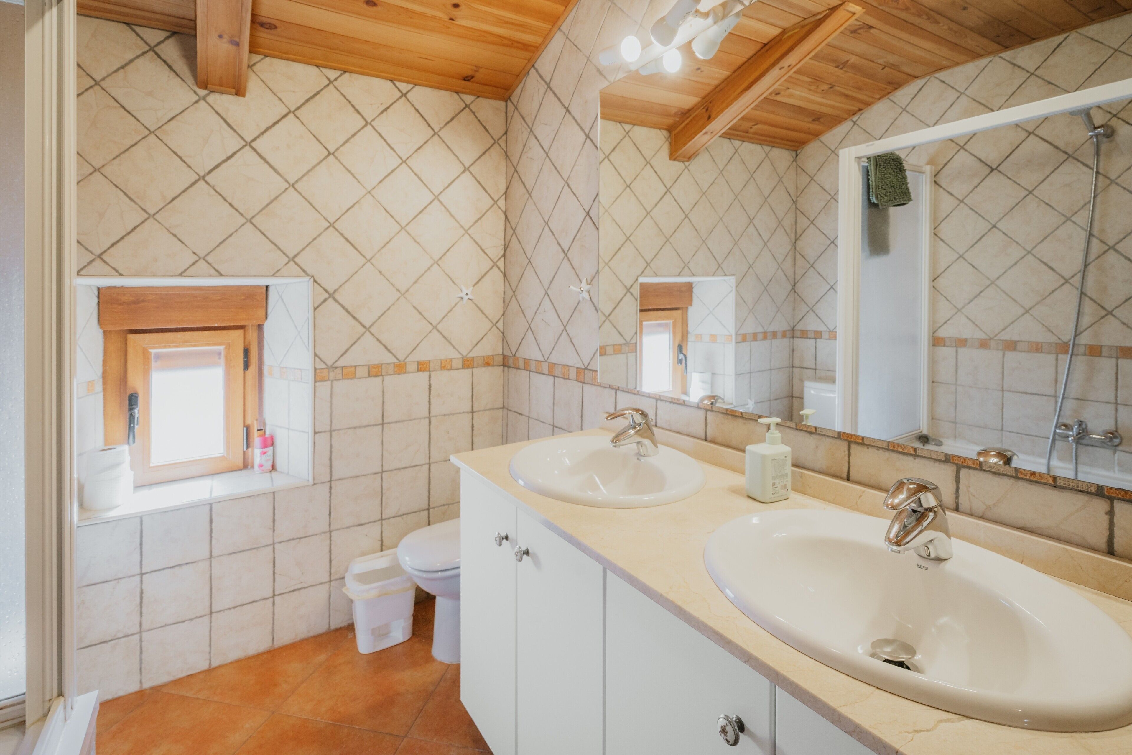 Une salle de bain avec deux lavabos, des toilettes et une fenêtre.
