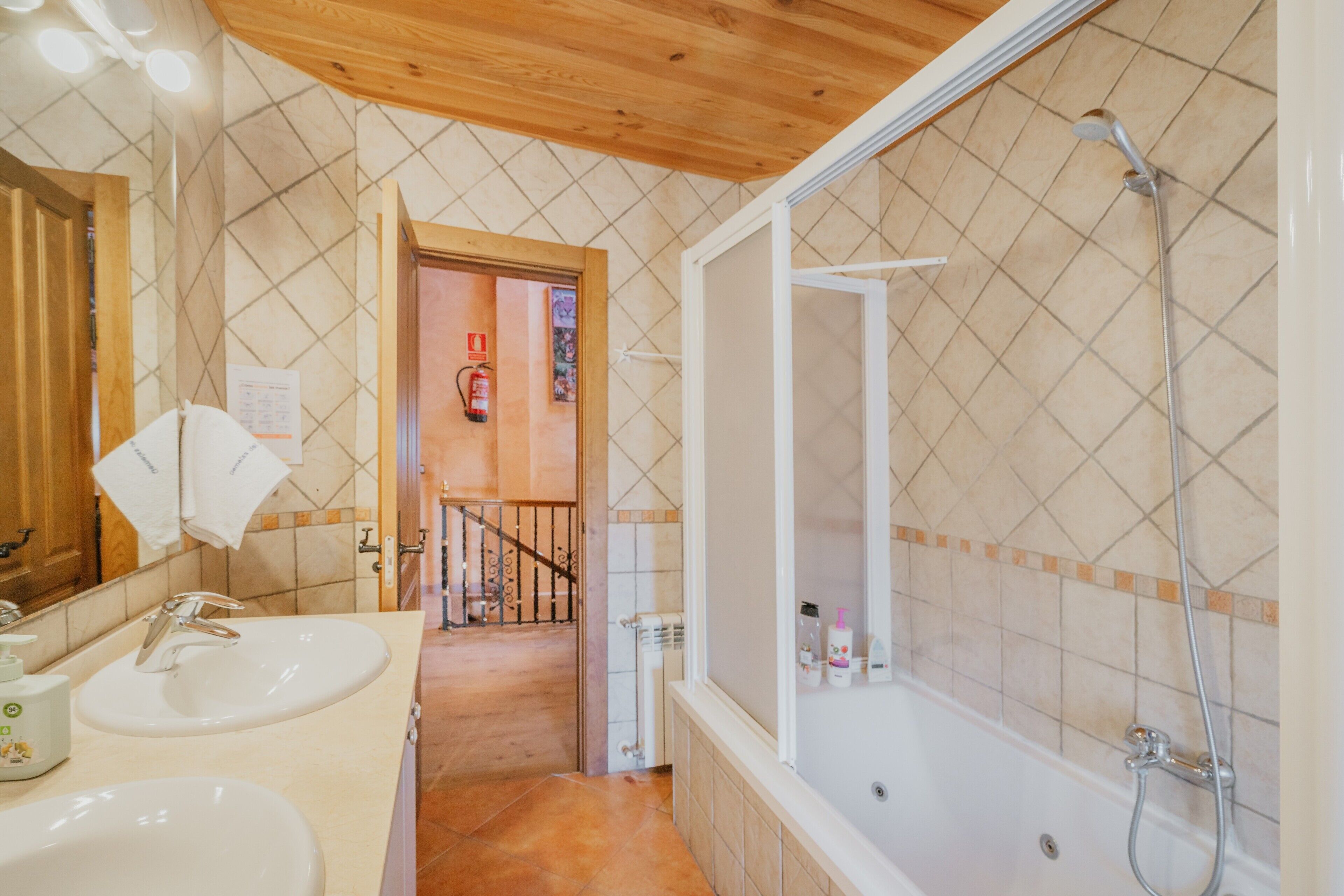A bathroom with two sinks, a shower, and a wooden ceiling.