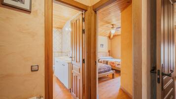 A wooden interior with a bathroom, a bed, and a ceiling fan.