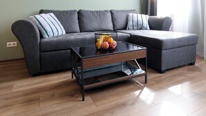 A modern living room with a sectional sofa, a glass coffee table, and a fruit basket. - ElbSuite 3 room apartment, 70sqm, old town and new town 10 minutes on foot (Dresden)