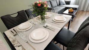 A dining table set for four with a vase of flowers, black chairs, and a grey patterned table runner. - ElbSuite 3 room apartment, 70sqm, old town and new town 10 minutes on foot (Dresden)