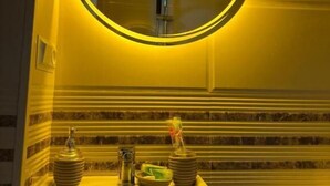 A bathroom with a round mirror, a sink, and a toilet. - Hotel sataplia (Tsqaltubo)