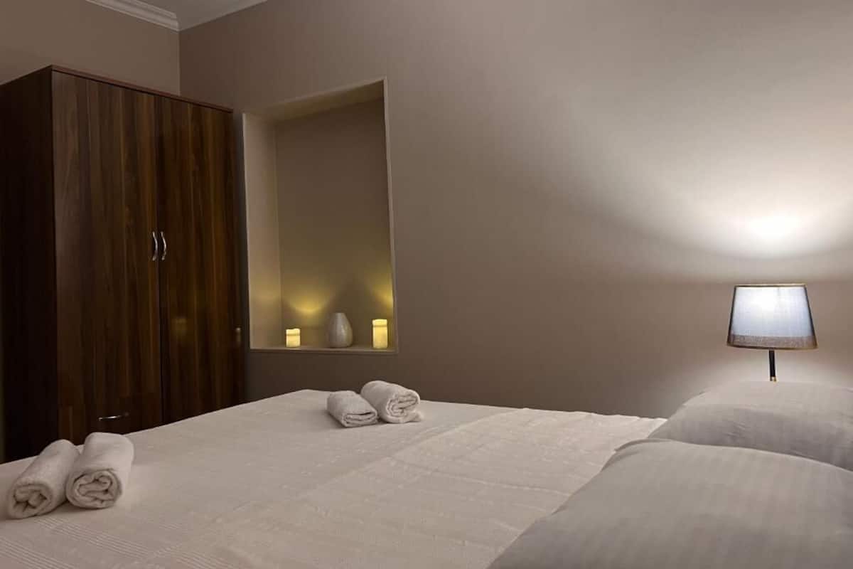 A hotel room with a bed, a wardrobe, a mirror, and a bedside lamp.