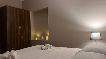 Habitación de hotel con cama, armario, espejo y lámpara de noche.