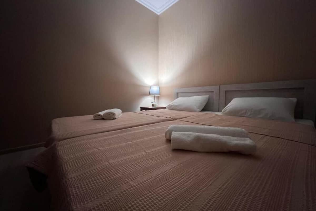 A hotel room with two beds, a nightstand with a lamp, and a skylight.