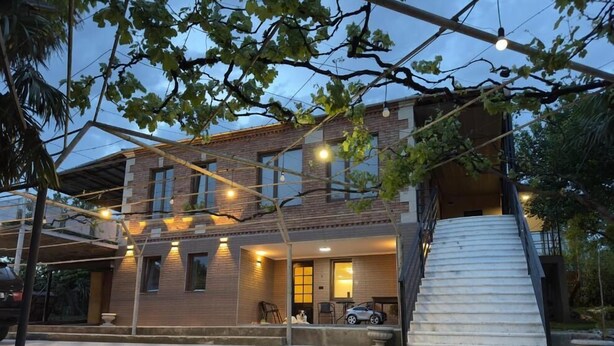 A modern two-story house with a covered patio area, outdoor seating, and a staircase leading to an upper level. - Hotel sataplia (Tsqaltubo)