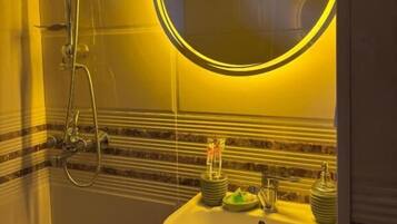 Un baño con ducha, lavamanos y espejo con luz circular.