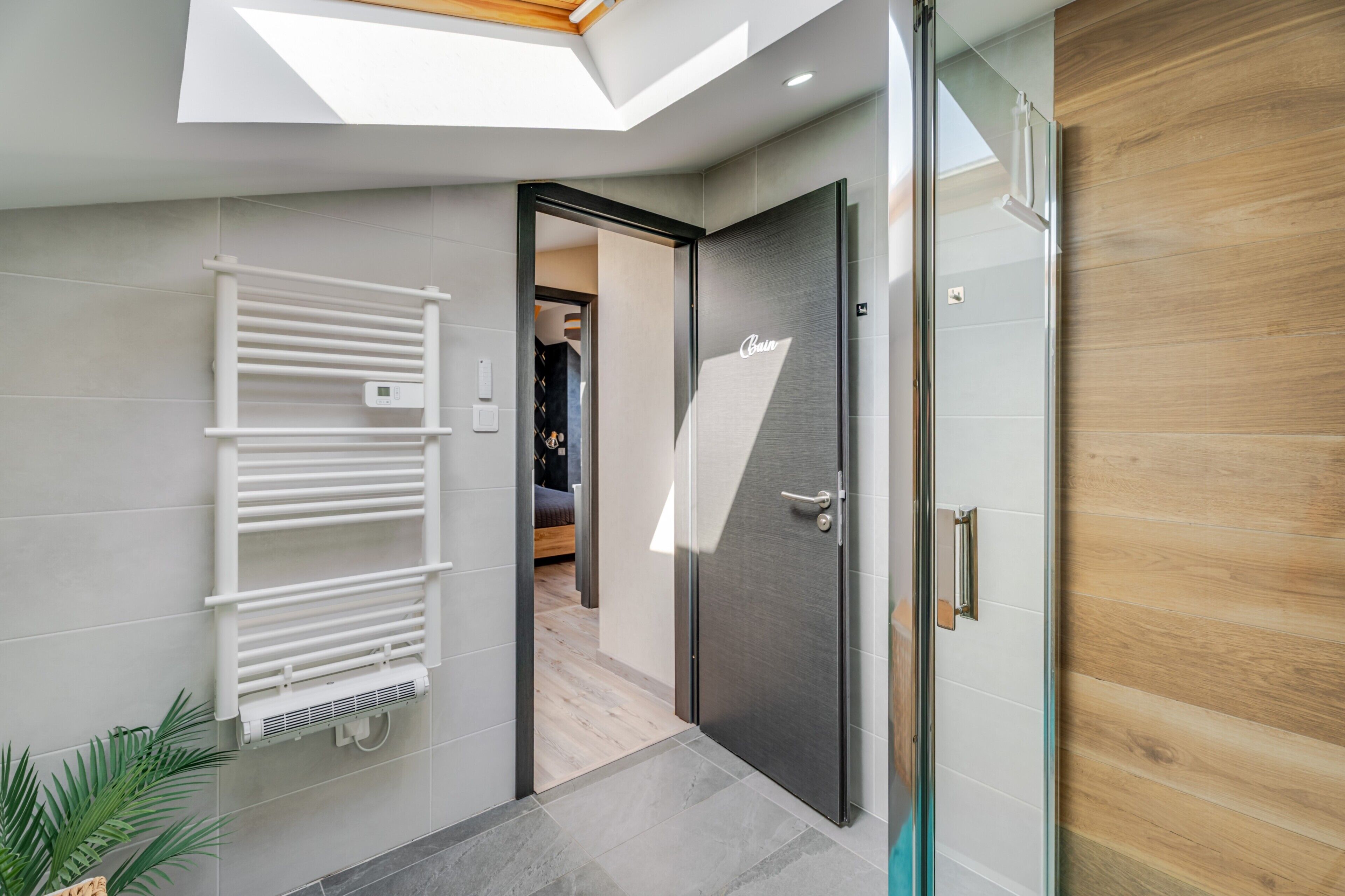Une salle de bain moderne avec une douche à parois de verre, un porte-serviettes et une porte en bois.