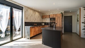 Una cocina moderna con armarios de madera, una isla central y un portón corredizo de vidrio que da a un espacio exterior.