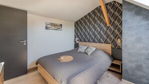 Un dormitorio con una cama, cabecera de madera, lámpara de pared, pared con diseño geométrico y una puerta.