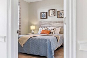 Une chambre à coucher avec un lit, une table de chevet, une lampe et des œuvres d’art murales.