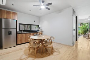 A modern kitchen with a built-in refrigerator, wooden cabinets, a round dining table with chairs, and a ceiling fan. - Resort Style Tulum Retreat | Private Plunge Pool (Tulum)