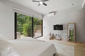 A bedroom with a bed, a TV, a mirror, and a sliding glass door to a balcony. - Resort Style Tulum Retreat | Private Plunge Pool (Tulum)