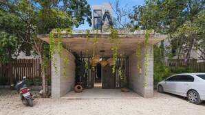 Un bâtiment moderne avec une entrée en béton, une voiture garée et une moto.