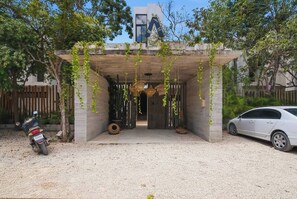 A modern building with a concrete entrance, a parked car, and a motorcycle. - Resort Style Tulum Retreat | Private Plunge Pool (Tulum)
