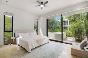 A bedroom with a bed, a ceiling fan, a large window, and a view of greenery outside. - Resort Style Tulum Retreat | Private Plunge Pool (Tulum)