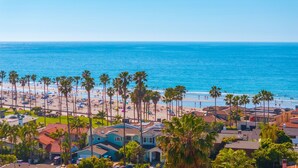 A coastal residential area with a beach, palm trees, and houses with red-tiled roofs. - Sunsets at the Shore House (San Diego)