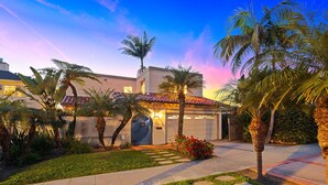 A residential property with a garage, palm trees, and a well-maintained lawn. - Sunsets at the Shore House (San Diego)