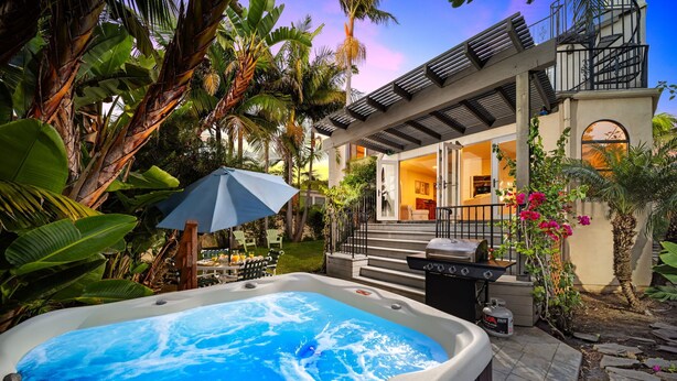 A hot tub in a tropical garden setting with a house in the background. - Sunsets at the Shore House (San Diego)