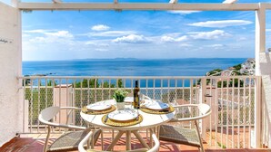 A balcony with a table set for two, overlooking a coastal view. - MALLORCA 13 Canyelles Roses (Rosas / Roses)